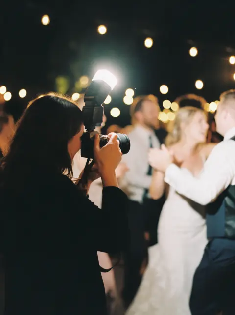 Fotógrafa com flash registrando a pista de dança de um casamento.